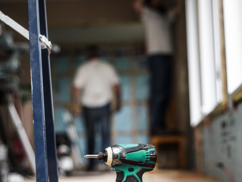 Battery Drill on the Floor with Worker in Background